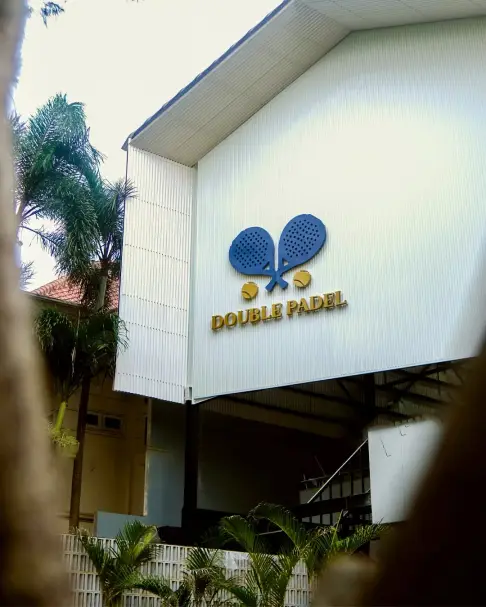 The white gabled Double Padel building among palms